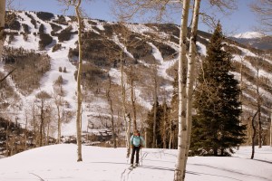 Kristine skinning thru gladed areas with Vail ski mountain behind